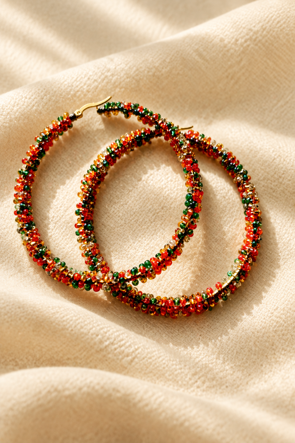Multicolor beaded hoop earrings on warm cream fabric