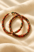 Multicolor beaded hoop earrings on warm cream fabric