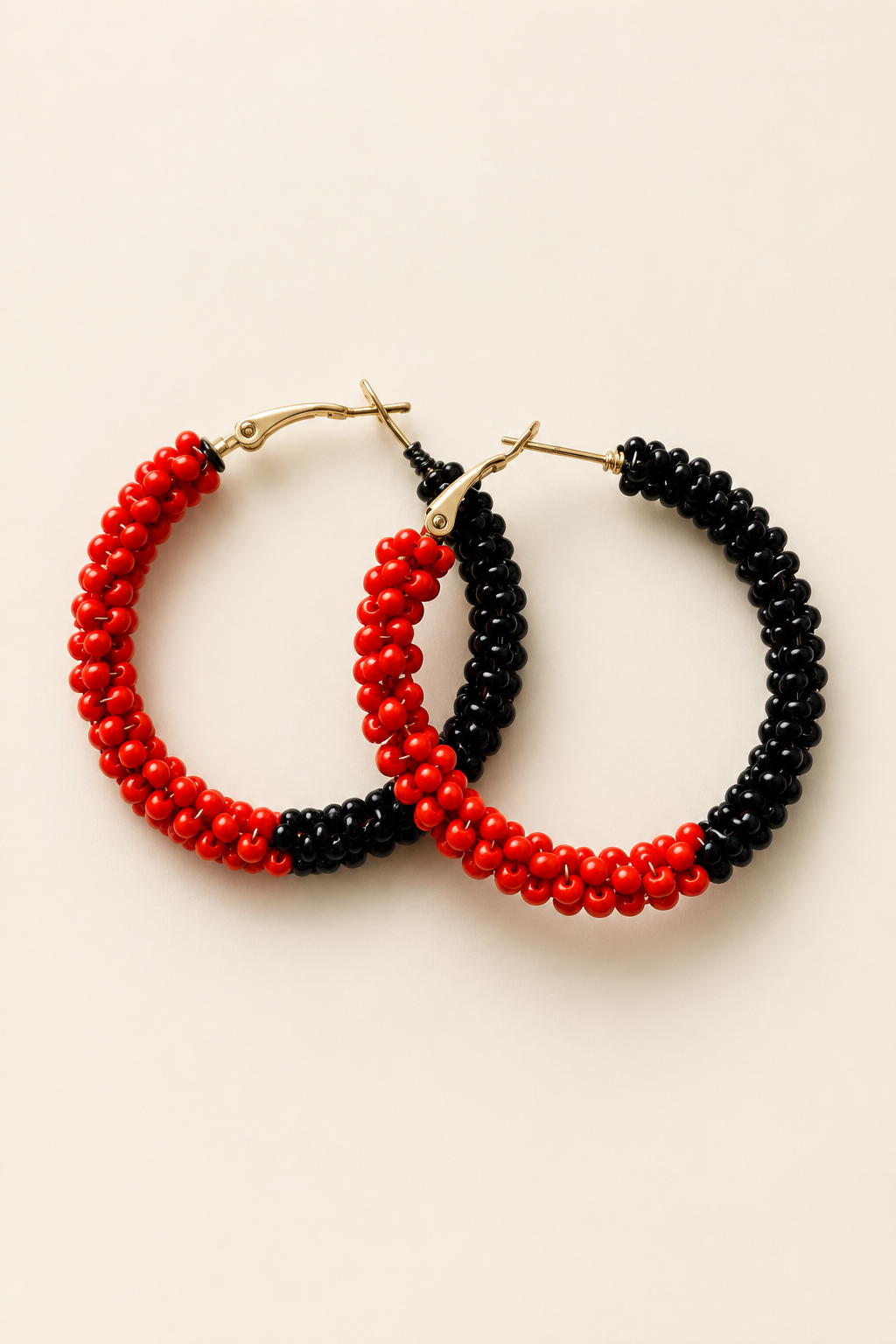 Red and black beaded earrings on a warm ivory background
