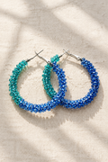 Teal and blue beaded earrings on light linen